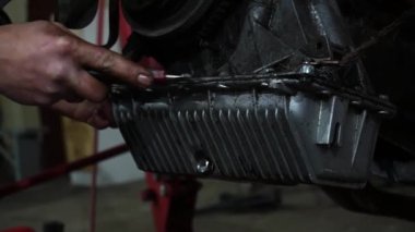 Bir tamirci tamir ve akort için kırmızı asansörde eski kirli bir araba motorunu söker.