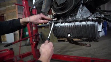 Bir tamirci tamir ve akort için kırmızı asansörde eski kirli bir araba motorunu söker.