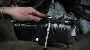 Bir tamirci tamir ve akort için kırmızı asansörde eski kirli bir araba motorunu söker.