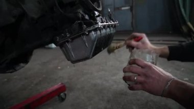 Bir tamirci tamir ve akort için kırmızı asansörde eski kirli bir araba motorunu söker.