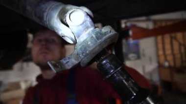 Cardan şaftı bir tamirci onarmak ve akort etmek için kırmızı asansörde eski bir kirli araba motorunu söker.