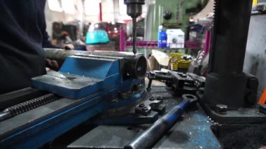 Bir çilingir metal sondaj yapar, bir araba için özel parçalar yapar.