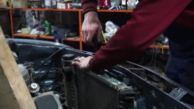 Bir tamirci tamir ve akort için kırmızı asansörde eski kirli bir araba motorunu söker.