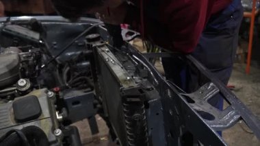 Bir tamirci tamir ve akort için kırmızı asansörde eski kirli bir araba motorunu söker.