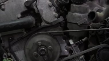 Bir tamirci tamir ve akort için kırmızı asansörde eski kirli bir araba motorunu söker.