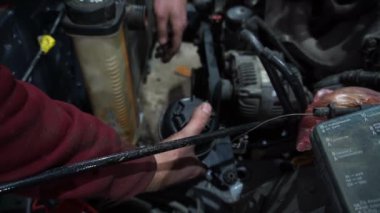 Bir tamirci tamir ve akort için kırmızı asansörde eski kirli bir araba motorunu söker.