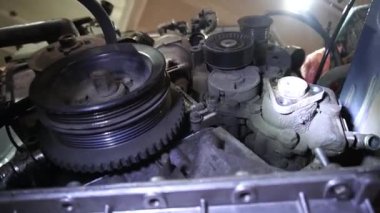 Bir tamirci tamir ve akort için kırmızı asansörde eski kirli bir araba motorunu söker.