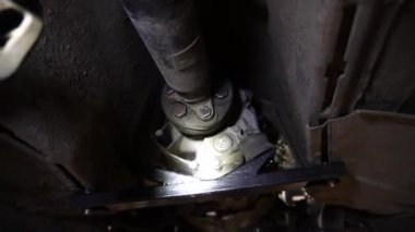 Cardan şaftı bir tamirci onarmak ve akort etmek için kırmızı asansörde eski bir kirli araba motorunu söker.