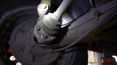 Cardan şaftı bir tamirci onarmak ve akort etmek için kırmızı asansörde eski bir kirli araba motorunu söker.