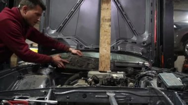 Bir tamirci tamir ve akort için kırmızı asansörde eski kirli bir araba motorunu söker.