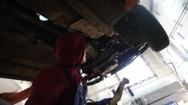 Bir tamirci tamir ve akort için kırmızı asansörde eski kirli bir araba motorunu söker.
