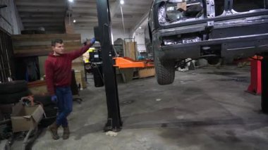 Bir tamirci tamir ve akort için kırmızı asansörde eski kirli bir araba motorunu söker.