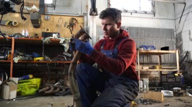 Bir tamirci tamir ve akort için kırmızı asansörde eski kirli bir araba motorunu söker.