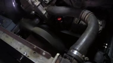 Bir tamirci tamir ve akort için kırmızı asansörde eski kirli bir araba motorunu söker.