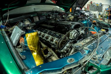 a mechanic disassembles an old dirty car engine on a red lift for repair and tuning turbo car