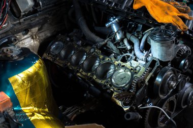 a mechanic disassembles an old dirty car engine on a red lift for repair and tuning turbo car