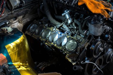 a mechanic disassembles an old dirty car engine on a red lift for repair and tuning turbo car