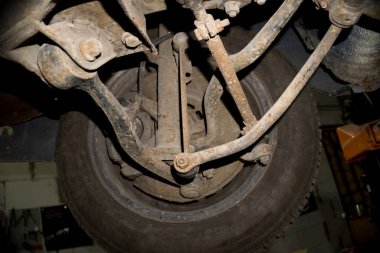a mechanic disassembles an old dirty car engine on a red lift for repair and tuning turbo car