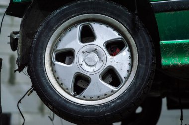 a mechanic disassembles an old dirty car engine on a red lift for repair and tuning turbo car
