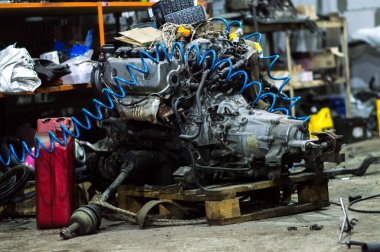 a mechanic disassembles an old dirty car engine on a red lift for repair and tuning turbo car