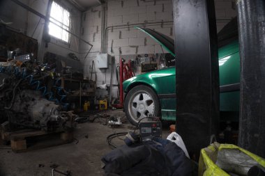 a mechanic disassembles an old dirty car engine on a red lift for repair and tuning turbo car