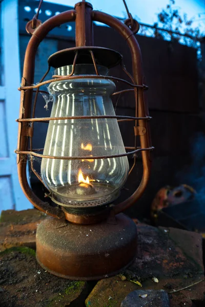 a red old kerosene lamp shines on a background of smoke and spins