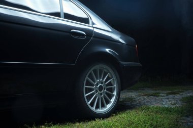 Bahçedeki eski siyah araba titanyum jantlar koyu arka planda dönen uzun pozlama videoları