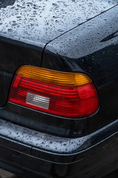 black car in the yard in water drops after rain with stylish taillights