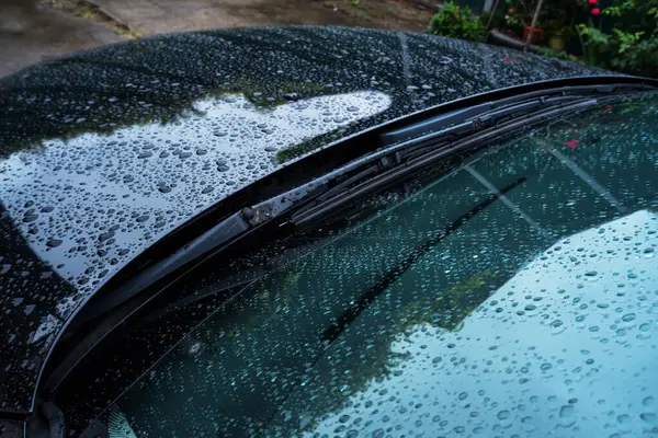 black car in the yard in water drops after rain with