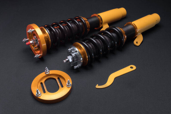 suspension tuning, coilovers, shock absorbers and front springs in yellow and gold colors for a sports drift car on a dark background