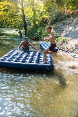 Bir çocuk sıcak bir günde yazın nehirde banyo yapar.