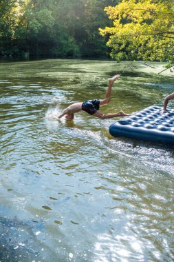Bir çocuk sıcak bir günde yazın nehirde banyo yapar.