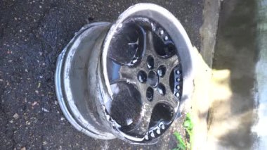 Araba tekerlekleri, titanyum jantlar, trafik kazasından sonra siyah, bahçedeki yeşil bir hortumdan gökkuşağı çıktı.