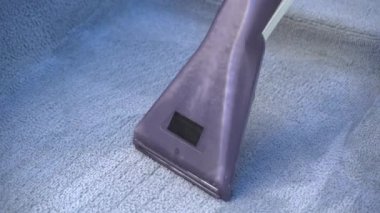 Evde elektrikli süpürgeyle çamurdan gri bir araba halısını yıkamak.