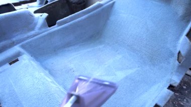 Evde elektrikli süpürgeyle çamurdan gri bir araba halısını yıkamak.