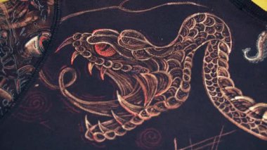 Yılan 2025, akrilik boyalarla boyanmış giysiler ve dövme makinesi kullanarak kumaşa çamaşır suyu.