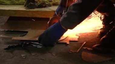 Eski bir arabanın egzoz sisteminin tamiri, öğütücüyle çalışmak, kaynak yapmak, gürültü emici yün yerleştirmek.