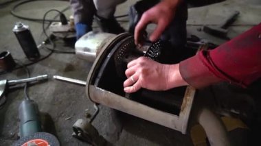 Eski bir arabanın egzoz sisteminin tamiri, öğütücüyle çalışmak, kaynak yapmak, gürültü emici yün yerleştirmek.