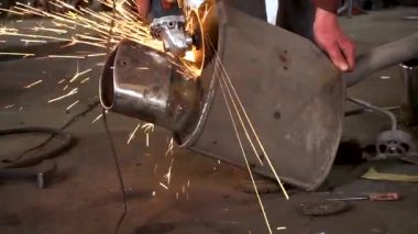 Eski bir arabanın egzoz sisteminin tamiri, öğütücüyle çalışmak, kaynak yapmak, gürültü emici yün yerleştirmek.