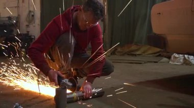 Eski bir arabanın egzoz sisteminin tamiri, öğütücüyle çalışmak, kaynak yapmak, gürültü emici yün yerleştirmek.