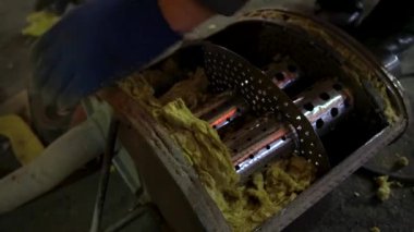 Eski bir arabanın egzoz sisteminin tamiri, öğütücüyle çalışmak, kaynak yapmak, gürültü emici yün yerleştirmek.