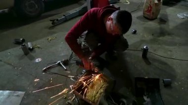 Eski bir arabanın egzoz sisteminin tamiri, öğütücüyle çalışmak, kaynak yapmak, gürültü emici yün yerleştirmek.