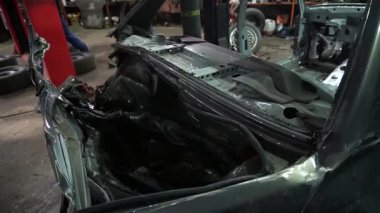 Özel egzoz sistemi ve egzoz manifoldu araba genç tamirci tamir ve eski gri bir araba monte bir trafik kazası sonra arka süspansiyon yeni sessiz bloklar baskı arka süspansiyon onarım ve yeni fren diskleri yükleme