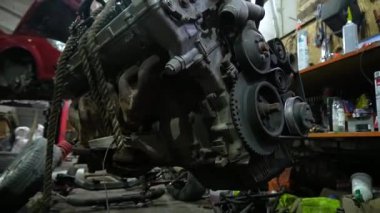 Özel egzoz sistemi ve egzoz manifoldu araba genç tamirci tamir ve eski gri bir araba monte bir trafik kazası sonra arka süspansiyon yeni sessiz bloklar baskı arka süspansiyon onarım ve yeni fren diskleri yükleme