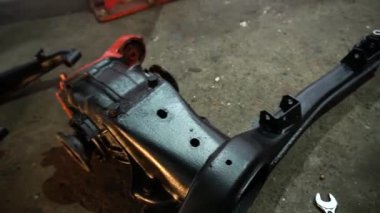 Özel egzoz sistemi ve egzoz manifoldu araba genç tamirci tamir ve eski gri bir araba monte bir trafik kazası sonra arka süspansiyon yeni sessiz bloklar baskı arka süspansiyon onarım ve yeni fren diskleri yükleme