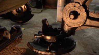 Özel egzoz sistemi ve egzoz manifoldu araba genç tamirci tamir ve eski gri bir araba monte bir trafik kazası sonra arka süspansiyon yeni sessiz bloklar baskı arka süspansiyon onarım ve yeni fren diskleri yükleme