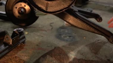 Özel egzoz sistemi ve egzoz manifoldu araba genç tamirci tamir ve eski gri bir araba monte bir trafik kazası sonra arka süspansiyon yeni sessiz bloklar baskı arka süspansiyon onarım ve yeni fren diskleri yükleme