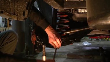 Özel egzoz sistemi ve egzoz manifoldu araba genç tamirci tamir ve eski gri bir araba monte bir trafik kazası sonra arka süspansiyon yeni sessiz bloklar baskı arka süspansiyon onarım ve yeni fren diskleri yükleme