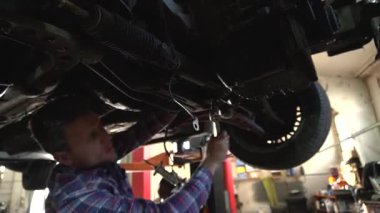 Özel egzoz sistemi ve egzoz manifoldu araba genç tamirci tamir ve eski gri bir araba monte bir trafik kazası sonra arka süspansiyon yeni sessiz bloklar baskı arka süspansiyon onarım ve yeni fren diskleri yükleme