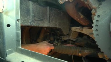 Özel egzoz sistemi ve egzoz manifoldu araba genç tamirci tamir ve eski gri bir araba monte bir trafik kazası sonra arka süspansiyon yeni sessiz bloklar baskı arka süspansiyon onarım ve yeni fren diskleri yükleme